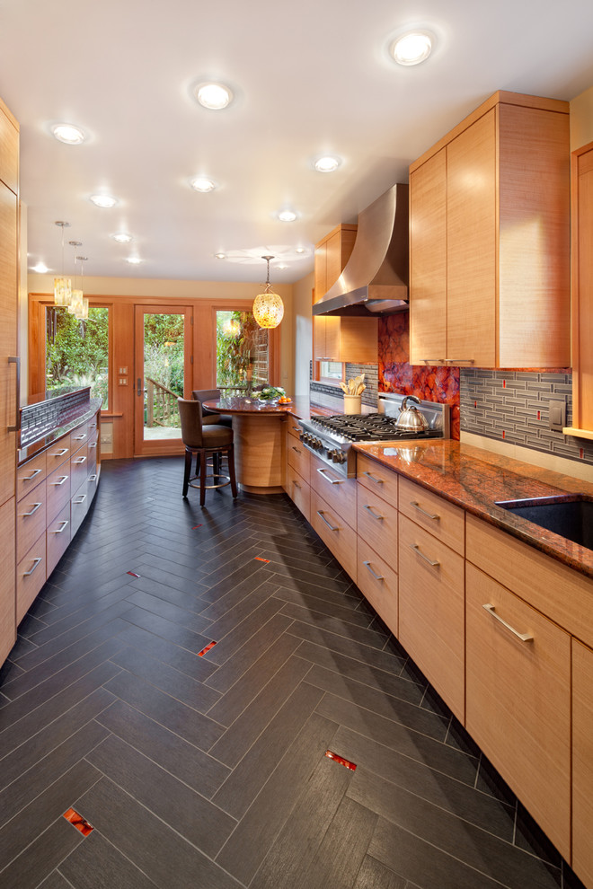 Example of a trendy galley enclosed kitchen design in Portland with an undermount sink, flat-panel cabinets, medium tone wood cabinets, granite countertops, gray backsplash, glass sheet backsplash, stainless steel appliances and orange countertops