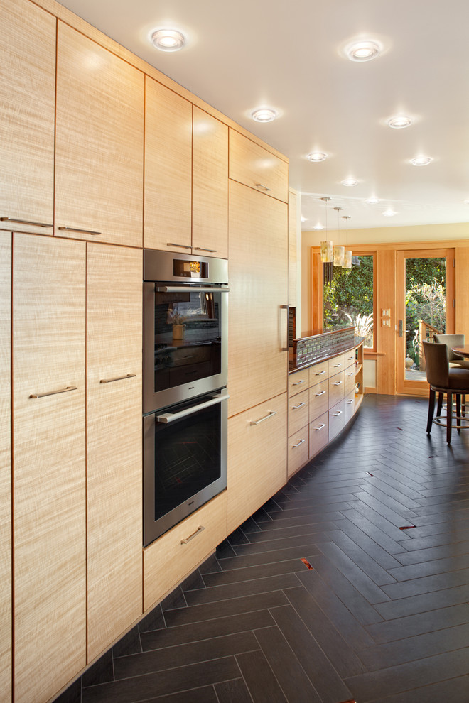 Стильный дизайн: кухня в современном стиле с техникой из нержавеющей стали, плоскими фасадами и фасадами цвета дерева среднего тона - последний тренд