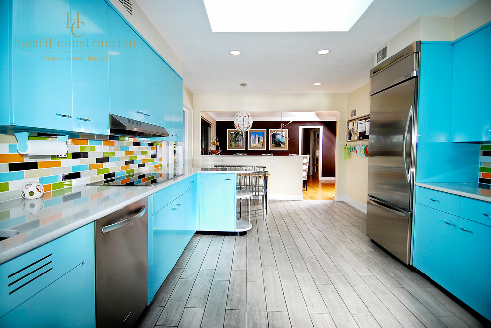 Inredning av ett 60 tals stort kök, med en dubbel diskho, släta luckor, blå skåp, flerfärgad stänkskydd, rostfria vitvaror, klinkergolv i keramik och grått golv
