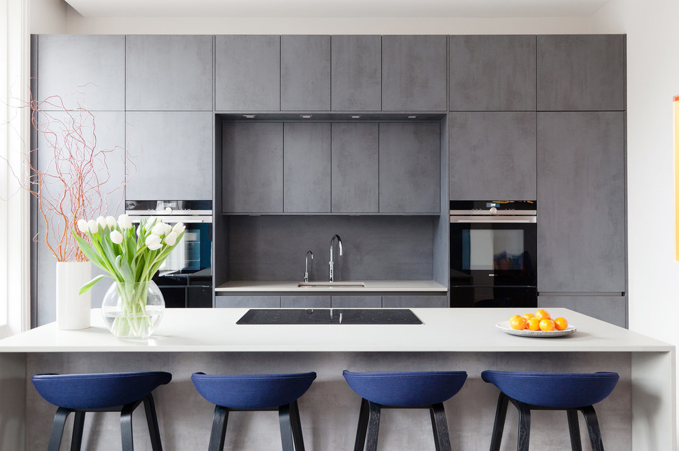 Inspiration for a medium sized contemporary kitchen in London with a submerged sink, flat-panel cabinets, grey cabinets, grey splashback, black appliances and an island.