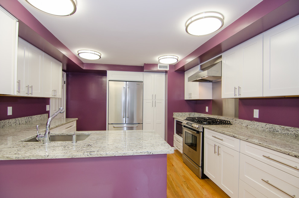 Example of a mid-sized trendy u-shaped light wood floor eat-in kitchen design in DC Metro with recessed-panel cabinets, white cabinets, granite countertops, stainless steel appliances, a peninsula and an undermount sink
