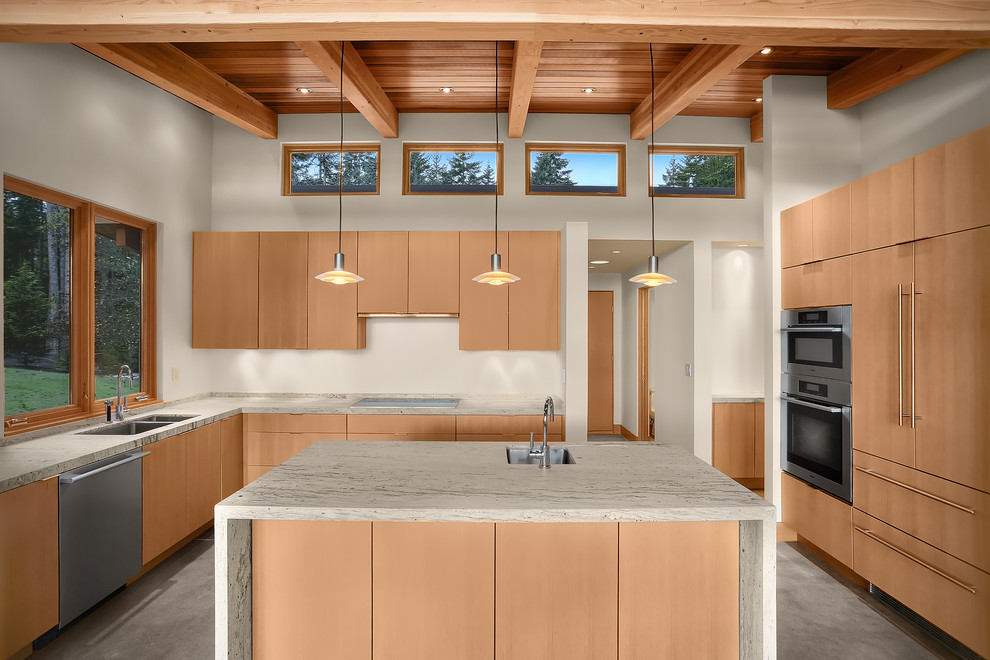 シアトルにあるコンテンポラリースタイルのおしゃれなキッチン (アンダーカウンターシンク、フラットパネル扉のキャビネット、淡色木目調キャビネット、シルバーの調理設備、コンクリートの床) の写真