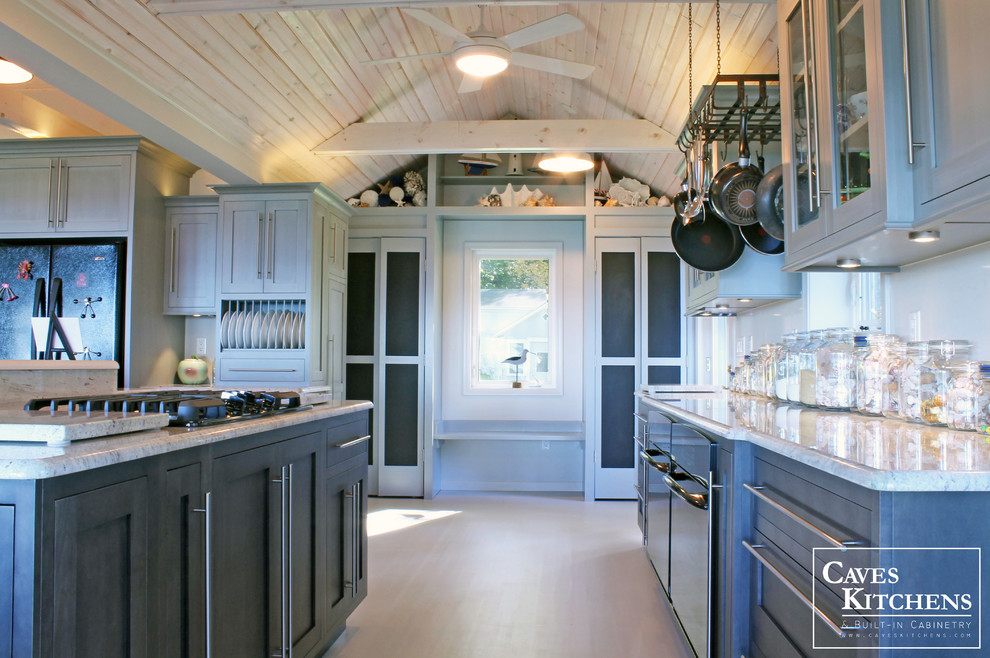 Example of a huge beach style l-shaped painted wood floor open concept kitchen design in New York with an undermount sink, recessed-panel cabinets, gray cabinets, granite countertops, white backsplash, black appliances and an island
