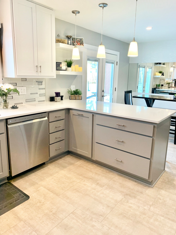 Inspiration for a mid-sized transitional u-shaped ceramic tile and black floor eat-in kitchen remodel in Other with an undermount sink, flat-panel cabinets, gray cabinets, quartz countertops, gray backsplash, glass tile backsplash, stainless steel appliances, a peninsula and white countertops
