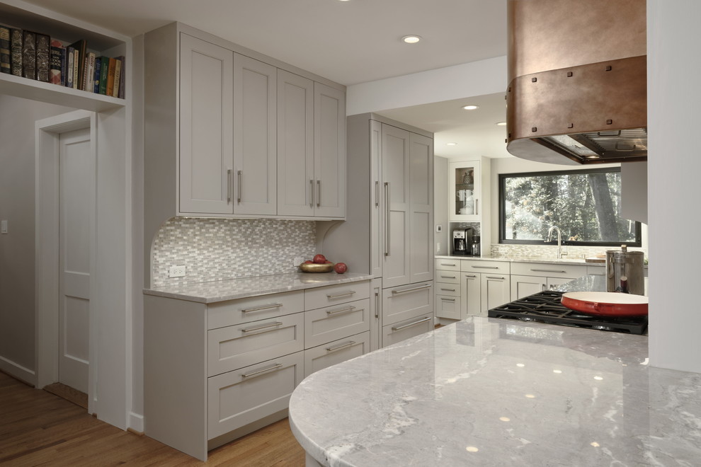 Klassisk inredning av ett stort grå grått kök, med en undermonterad diskho, skåp i shakerstil, grå skåp, bänkskiva i kvartsit, grått stänkskydd, stänkskydd i mosaik, rostfria vitvaror, mellanmörkt trägolv, en halv köksö och brunt golv