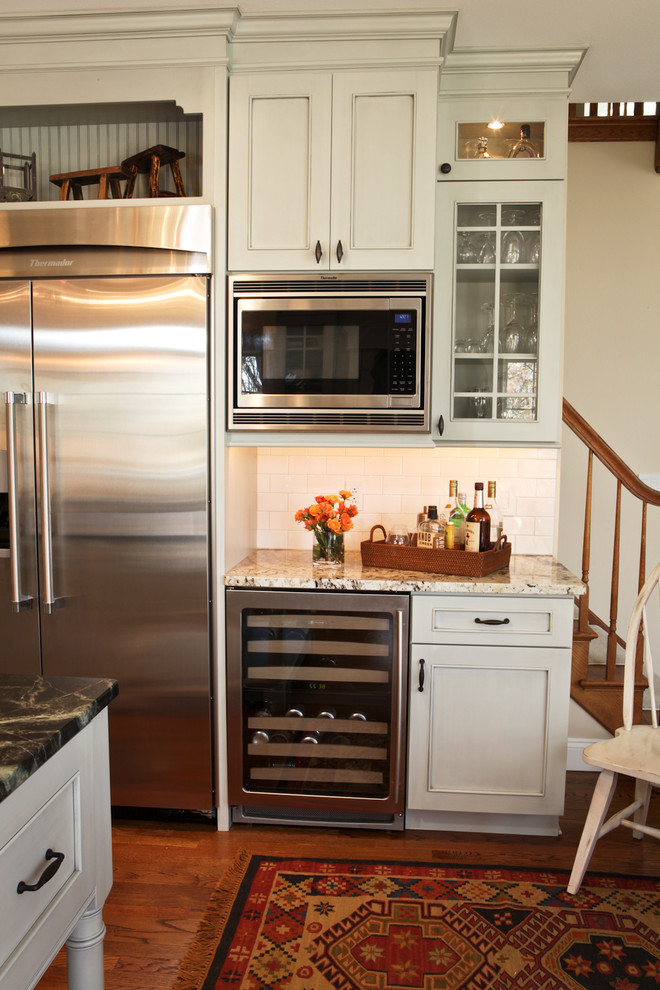 Exempel på ett mellanstort klassiskt kök, med en undermonterad diskho, luckor med infälld panel, grå skåp, bänkskiva i täljsten, vitt stänkskydd, stänkskydd i tunnelbanekakel, rostfria vitvaror, mellanmörkt trägolv och en köksö