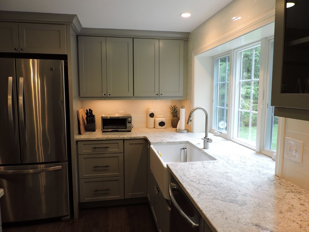 Bild på ett stort lantligt kök, med en rustik diskho, skåp i shakerstil, grå skåp, granitbänkskiva, vitt stänkskydd, stänkskydd i porslinskakel, rostfria vitvaror, mörkt trägolv och en köksö
