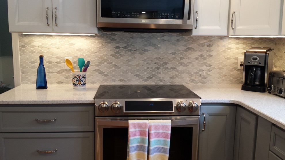 Klassisk inredning av ett mellanstort u-kök, med grå skåp, bänkskiva i kvarts, grått stänkskydd, stänkskydd i mosaik, rostfria vitvaror och en halv köksö