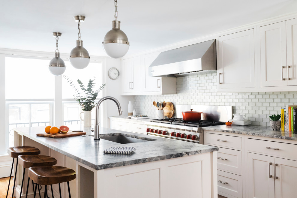 Transitional medium tone wood floor kitchen photo in Boston with an undermount sink, shaker cabinets, white cabinets, white backsplash, subway tile backsplash, stainless steel appliances, an island and multicolored countertops