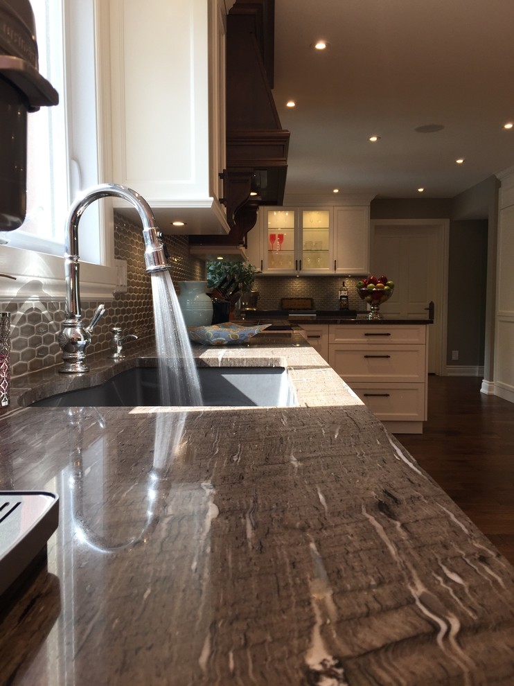 This is an example of an expansive traditional galley kitchen/diner in Montreal with a submerged sink, shaker cabinets, white cabinets, granite worktops, beige splashback, mosaic tiled splashback, stainless steel appliances, medium hardwood flooring and an island.