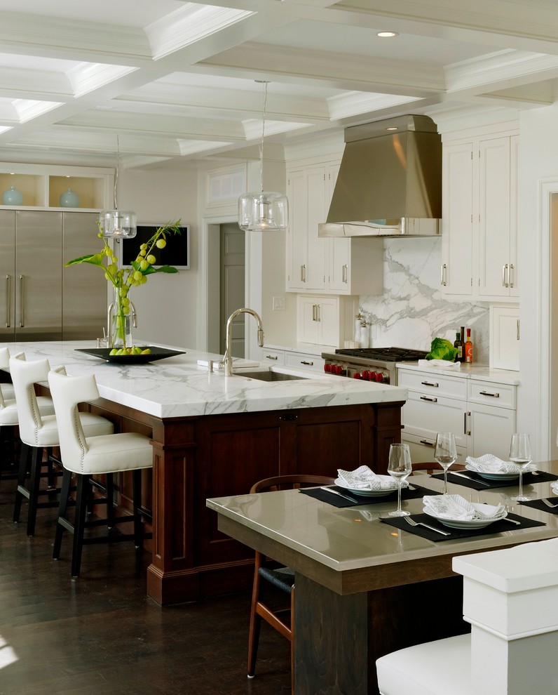 Klassisk inredning av ett stort kök, med en undermonterad diskho, skåp i shakerstil, vita skåp, vitt stänkskydd, mörkt trägolv, granitbänkskiva, rostfria vitvaror, en köksö och stänkskydd i sten