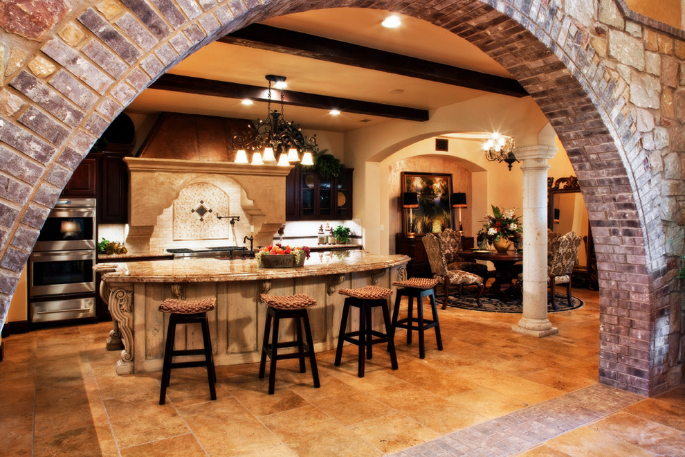 Example of a large tuscan l-shaped ceramic tile and beige floor open concept kitchen design in Austin with a farmhouse sink, raised-panel cabinets, dark wood cabinets, granite countertops, beige backsplash, ceramic backsplash, stainless steel appliances and an island