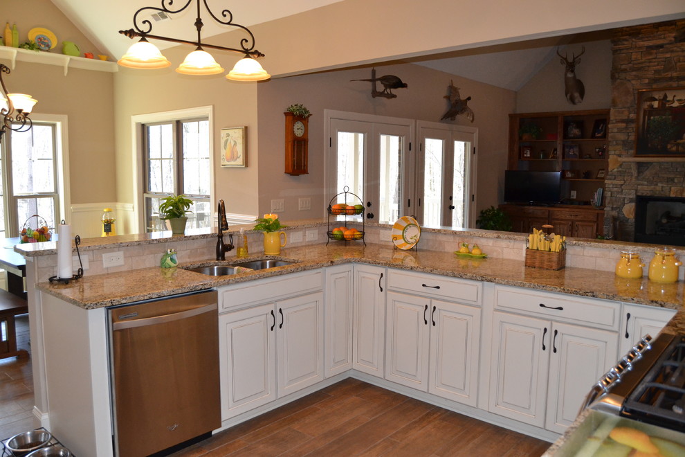 Cette image montre une cuisine ouverte chalet avec un plan de travail en granite, un électroménager en acier inoxydable, des portes de placard beiges et une crédence beige.