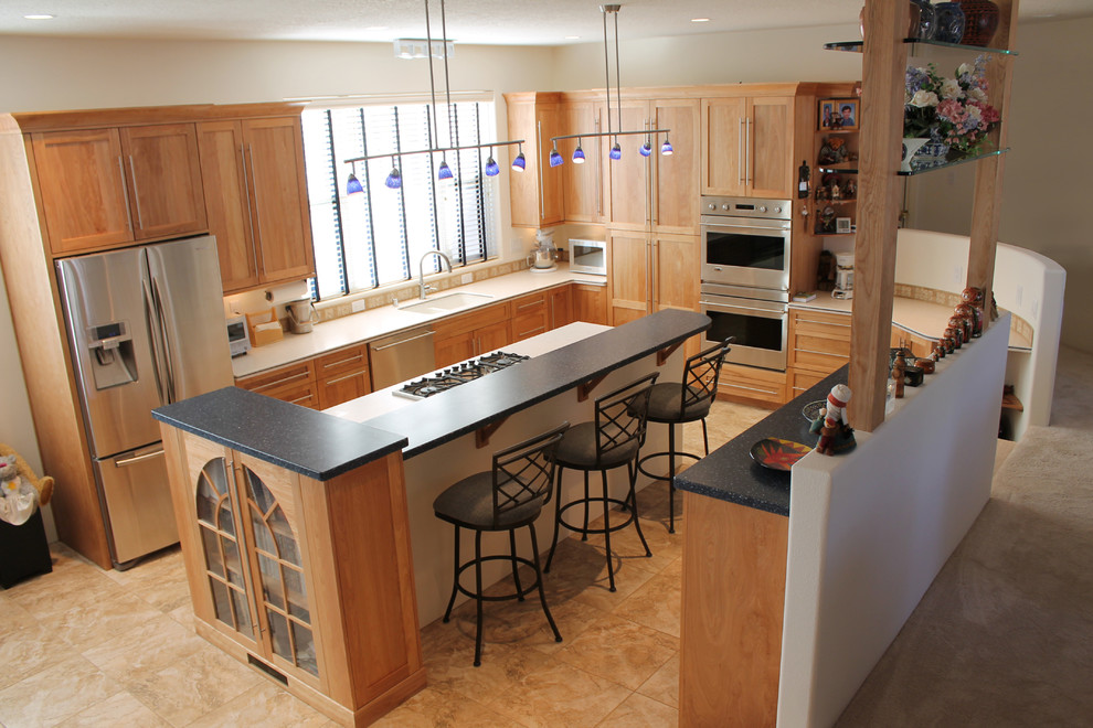 Example of a mid-sized transitional u-shaped porcelain tile open concept kitchen design in Albuquerque with a double-bowl sink, shaker cabinets, light wood cabinets, solid surface countertops, stainless steel appliances and an island