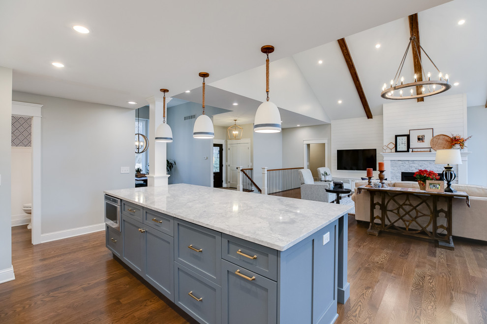 Inspiration for a large transitional l-shaped medium tone wood floor and brown floor open concept kitchen remodel in Minneapolis with an undermount sink, shaker cabinets, white cabinets, quartzite countertops, white backsplash, mosaic tile backsplash, stainless steel appliances, an island and white countertops