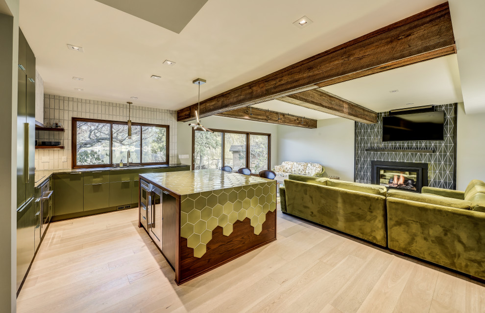 Modern inredning av ett mycket stort grön grönt kök, med gröna skåp, kaklad bänkskiva, vitt stänkskydd, stänkskydd i tegel, ljust trägolv, en köksö och beiget golv