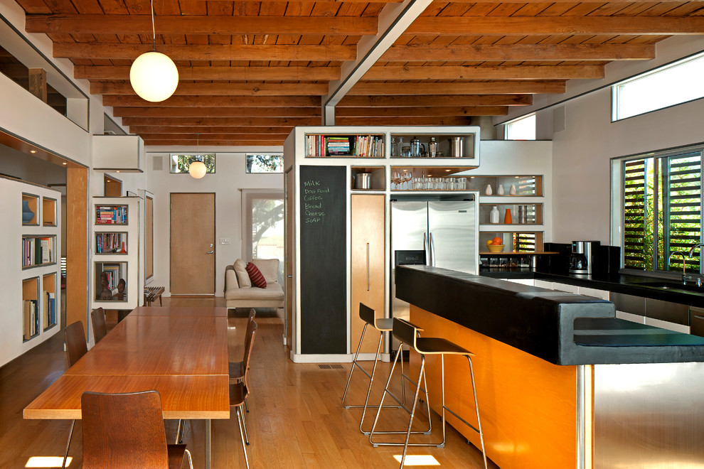 Idée de décoration pour une cuisine américaine design en L avec un sol en bois brun et îlot.