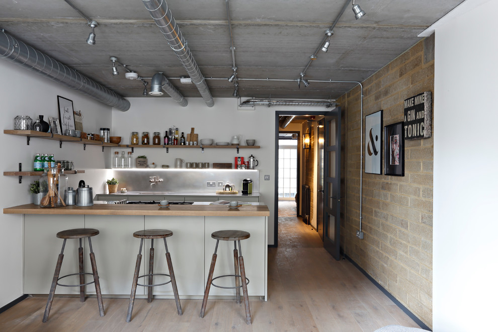 Industrial Küche mit Unterbauwaschbecken, Arbeitsplatte aus Holz, Küchengeräten aus Edelstahl und braunem Holzboden in London