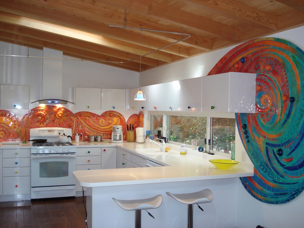 На фото: п-образная кухня в современном стиле с монолитной мойкой, плоскими фасадами, белыми фасадами, оранжевым фартуком и белой техникой