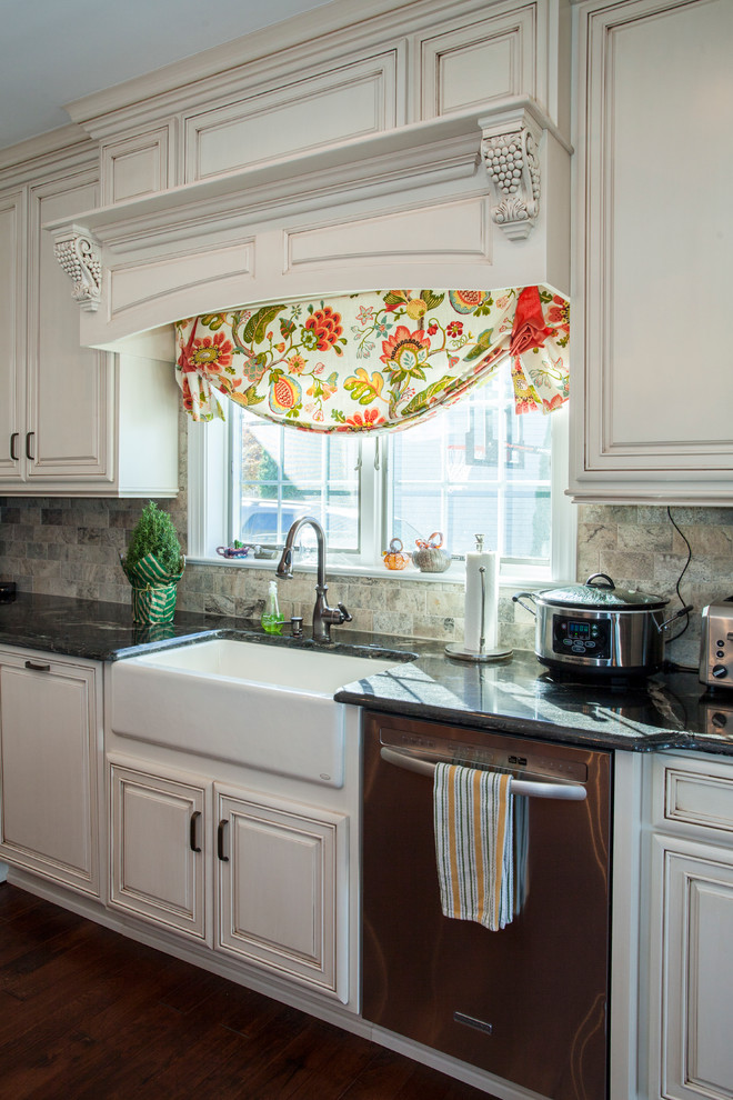 Example of a large classic l-shaped dark wood floor eat-in kitchen design in Philadelphia with a farmhouse sink, raised-panel cabinets, white cabinets, granite countertops, multicolored backsplash, stone slab backsplash, stainless steel appliances and an island