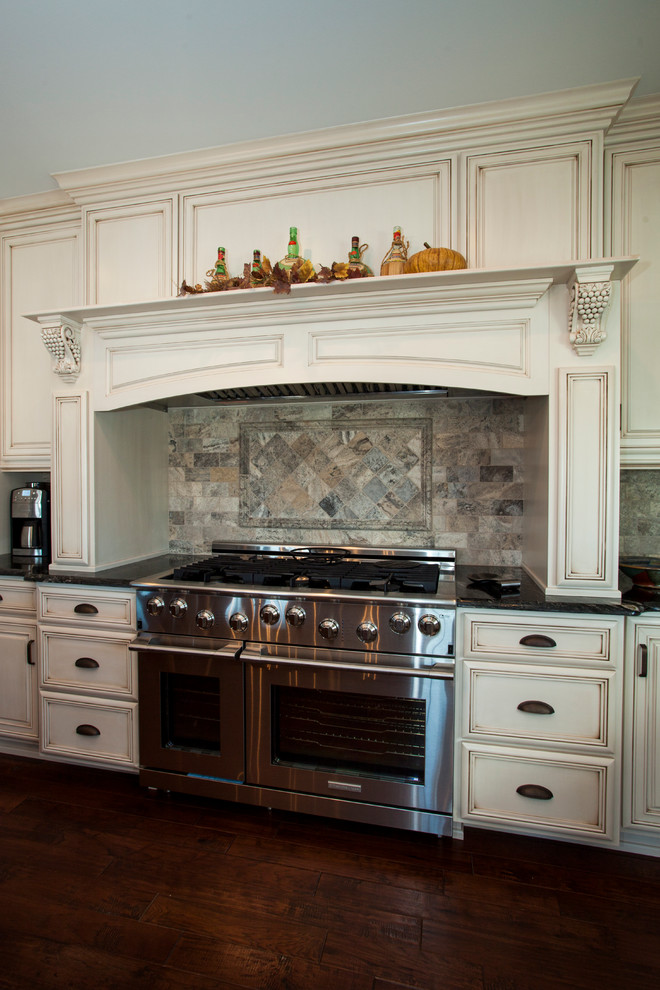 Foto på ett stort vintage kök, med en rustik diskho, luckor med upphöjd panel, beige skåp, granitbänkskiva, flerfärgad stänkskydd, stänkskydd i stenkakel, rostfria vitvaror, mörkt trägolv och en köksö