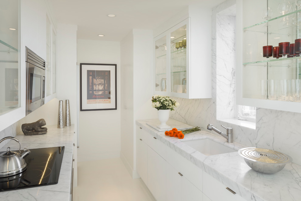 Zweizeilige Moderne Küche mit Unterbauwaschbecken, Glasfronten, weißen Schränken, Marmor-Arbeitsplatte, Küchenrückwand in Weiß und Küchengeräten aus Edelstahl in San Francisco