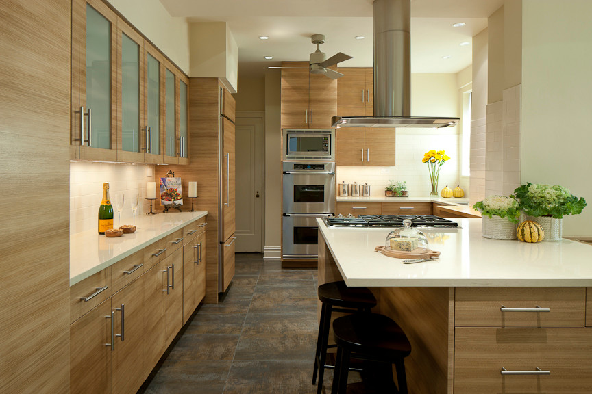 Example of a mid-sized trendy l-shaped ceramic tile eat-in kitchen design in Chicago with a drop-in sink, medium tone wood cabinets, solid surface countertops, white backsplash, ceramic backsplash, stainless steel appliances, a peninsula and flat-panel cabinets