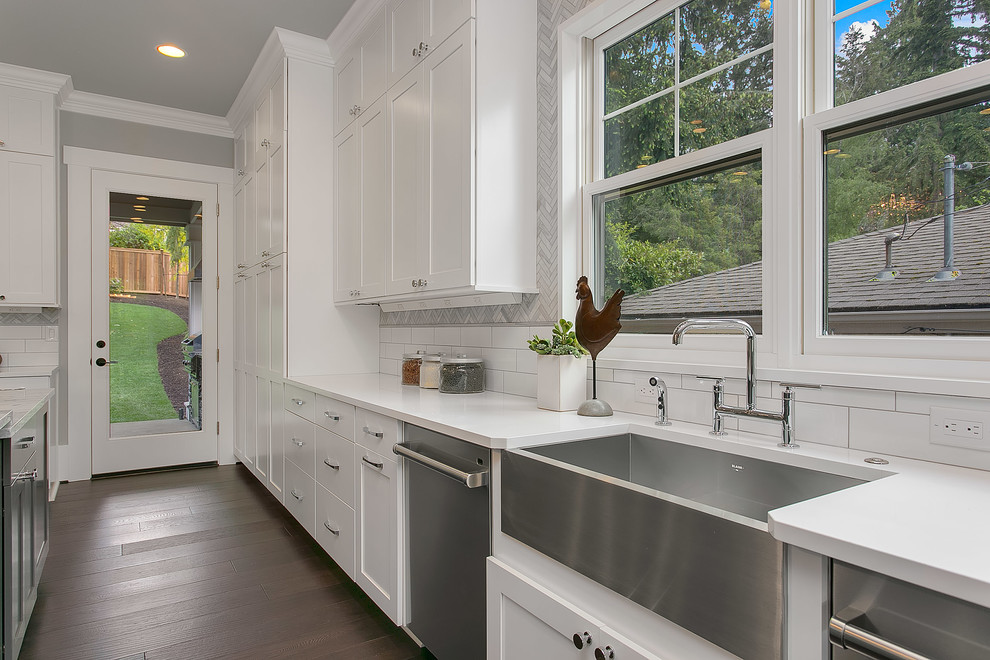 Photo of an expansive classic u-shaped kitchen/diner in Seattle with a belfast sink, flat-panel cabinets, white cabinets, marble worktops, multi-coloured splashback, stainless steel appliances, dark hardwood flooring and an island.