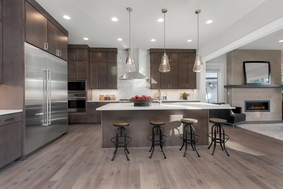 This is an example of a large contemporary single-wall kitchen/diner in Seattle with a submerged sink, flat-panel cabinets, dark wood cabinets, engineered stone countertops, white splashback, stainless steel appliances, medium hardwood flooring, an island and grey floors.
