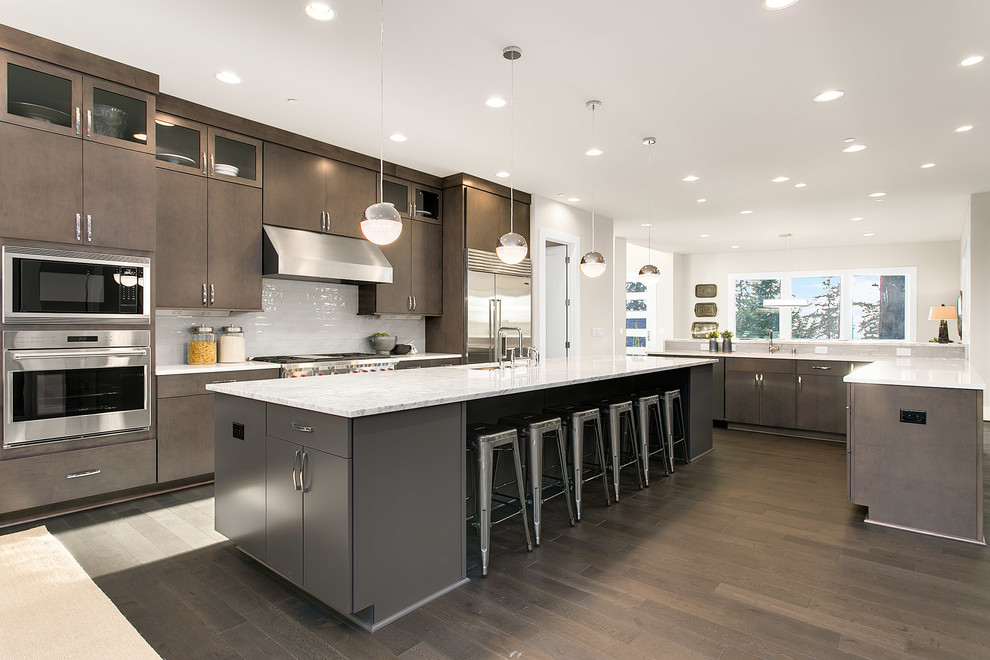 Moderne Küche mit flächenbündigen Schrankfronten, Quarzwerkstein-Arbeitsplatte, Küchengeräten aus Edelstahl, Unterbauwaschbecken, dunklen Holzschränken, Küchenrückwand in Weiß und dunklem Holzboden in Seattle