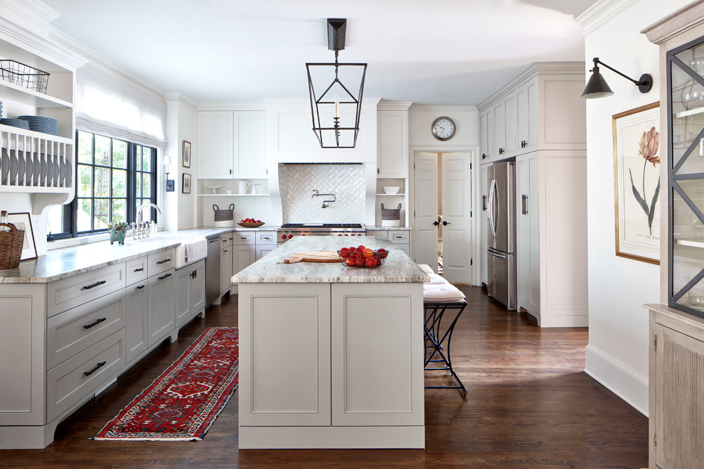 Geschlossene Klassische Küche in L-Form mit Landhausspüle, Schrankfronten mit vertiefter Füllung, weißen Schränken, Küchenrückwand in Weiß, Küchengeräten aus Edelstahl, dunklem Holzboden und Kücheninsel in Atlanta