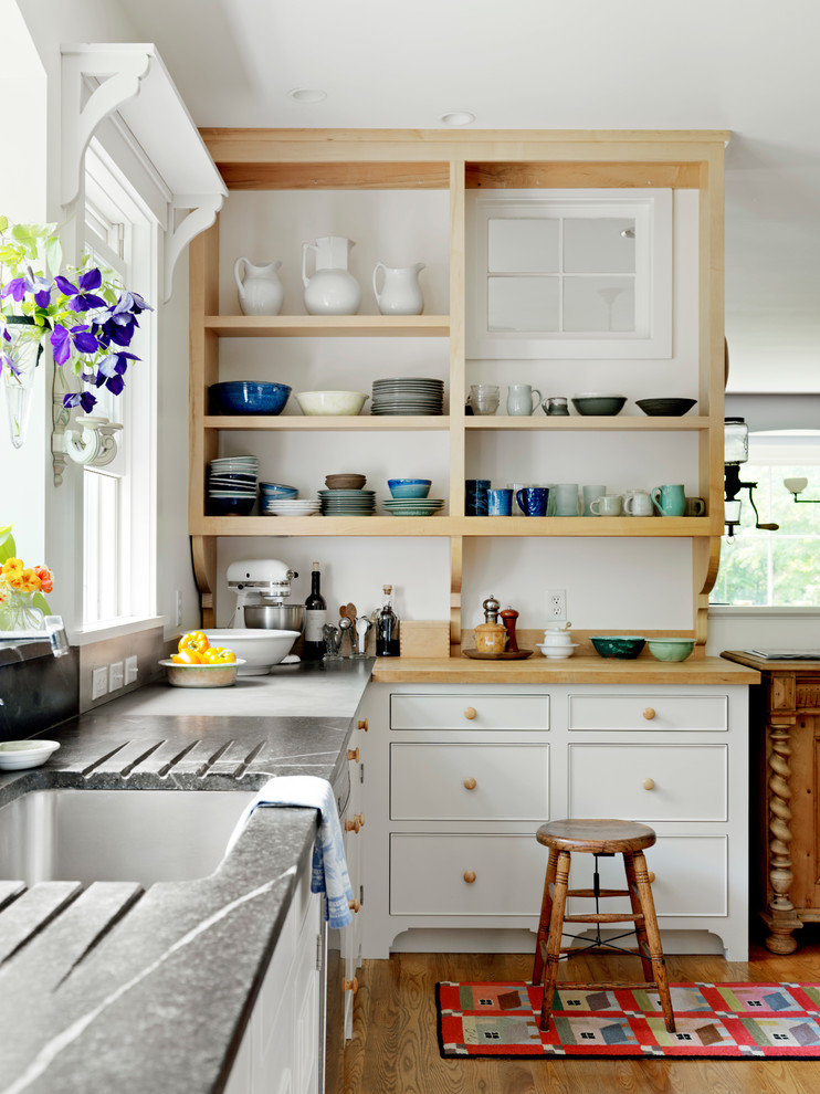 Example of a farmhouse kitchen design in Burlington with an undermount sink, open cabinets and wood countertops