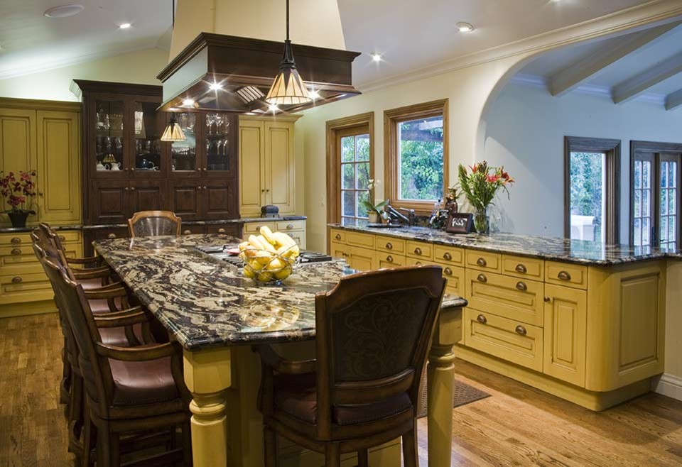 Medium sized traditional kitchen/diner in San Francisco with a submerged sink, raised-panel cabinets, yellow cabinets, granite worktops, stainless steel appliances, medium hardwood flooring and multiple islands.