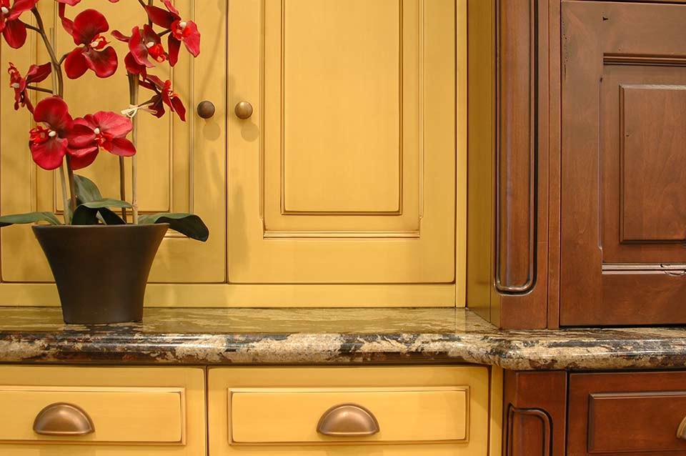 Inredning av ett klassiskt mellanstort kök och matrum, med en undermonterad diskho, luckor med upphöjd panel, gula skåp, granitbänkskiva, rostfria vitvaror, mellanmörkt trägolv och flera köksöar