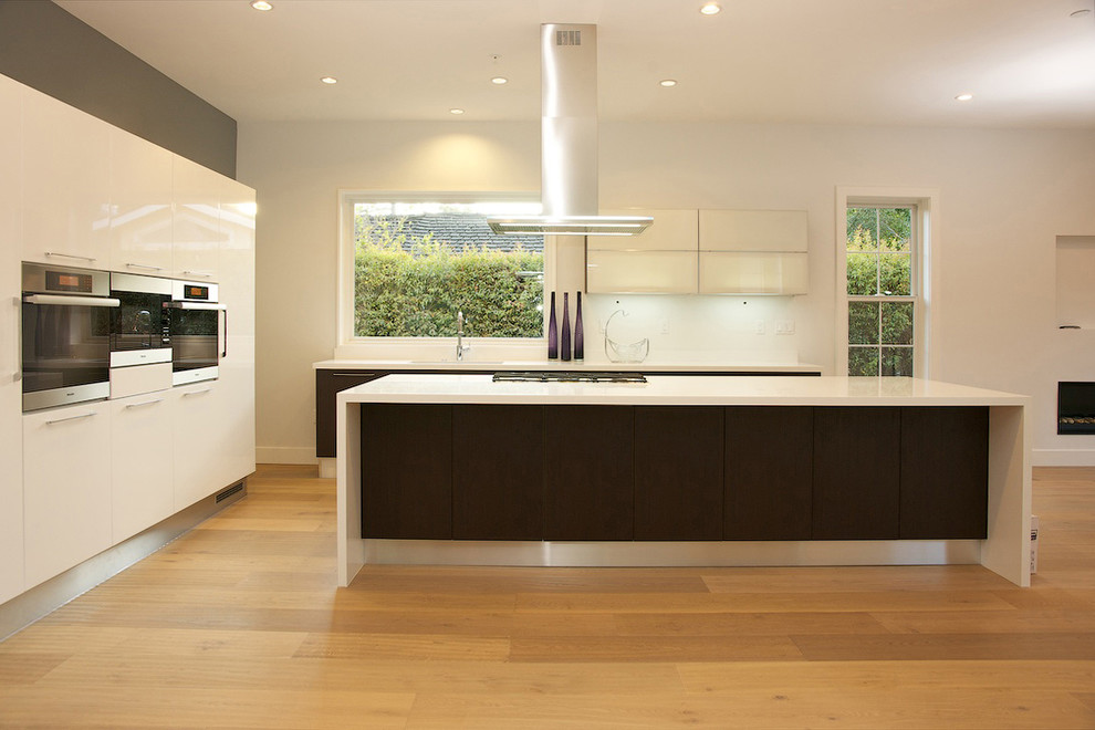 Imagen de cocina actual con armarios con paneles lisos, puertas de armario blancas y electrodomésticos de acero inoxidable