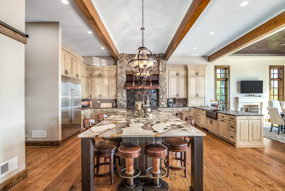 This is an example of a rustic u-shaped kitchen in Chicago with a belfast sink, raised-panel cabinets, medium wood cabinets, black splashback, stainless steel appliances, medium hardwood flooring, an island, brown floors and black worktops.