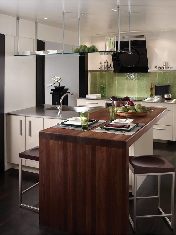 Kleine Moderne Wohnküche in L-Form mit integriertem Waschbecken, flächenbündigen Schrankfronten, beigen Schränken, Edelstahl-Arbeitsplatte, Küchenrückwand in Grün, Glasrückwand, schwarzen Elektrogeräten, Vinylboden und zwei Kücheninseln in Houston