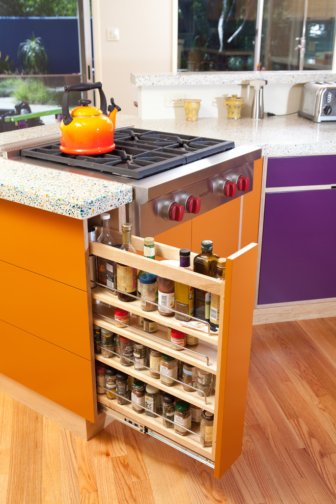 Inspiration for a mid-sized eclectic u-shaped medium tone wood floor and brown floor eat-in kitchen remodel in San Luis Obispo with flat-panel cabinets, stainless steel appliances, an undermount sink, light wood cabinets, blue backsplash, subway tile backsplash, a peninsula, recycled glass countertops and multicolored countertops