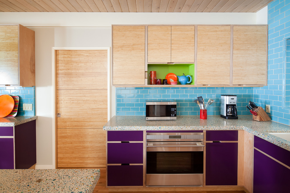 Exempel på ett mellanstort eklektiskt flerfärgad flerfärgat kök, med rostfria vitvaror, släta luckor, skåp i ljust trä, stänkskydd i tunnelbanekakel, en undermonterad diskho, blått stänkskydd, mellanmörkt trägolv, en halv köksö, brunt golv och bänkskiva i återvunnet glas