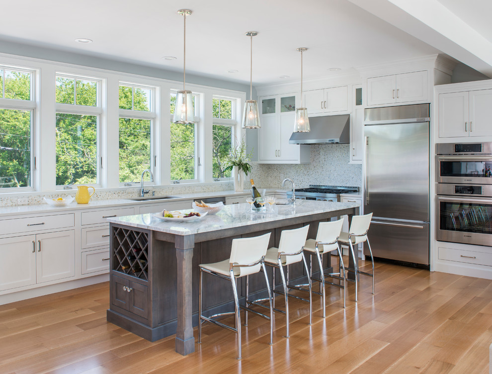 Open concept kitchen - mid-sized coastal u-shaped light wood floor open concept kitchen idea in Providence with an undermount sink, beaded inset cabinets, white cabinets, marble countertops, white backsplash, mosaic tile backsplash, stainless steel appliances and an island