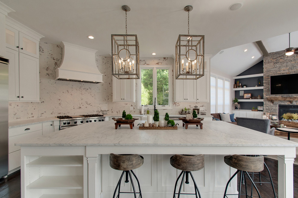 Large transitional l-shaped dark wood floor and brown floor open concept kitchen photo in Nashville with a farmhouse sink, shaker cabinets, white cabinets, marble countertops, white backsplash, brick backsplash, stainless steel appliances, an island and white countertops