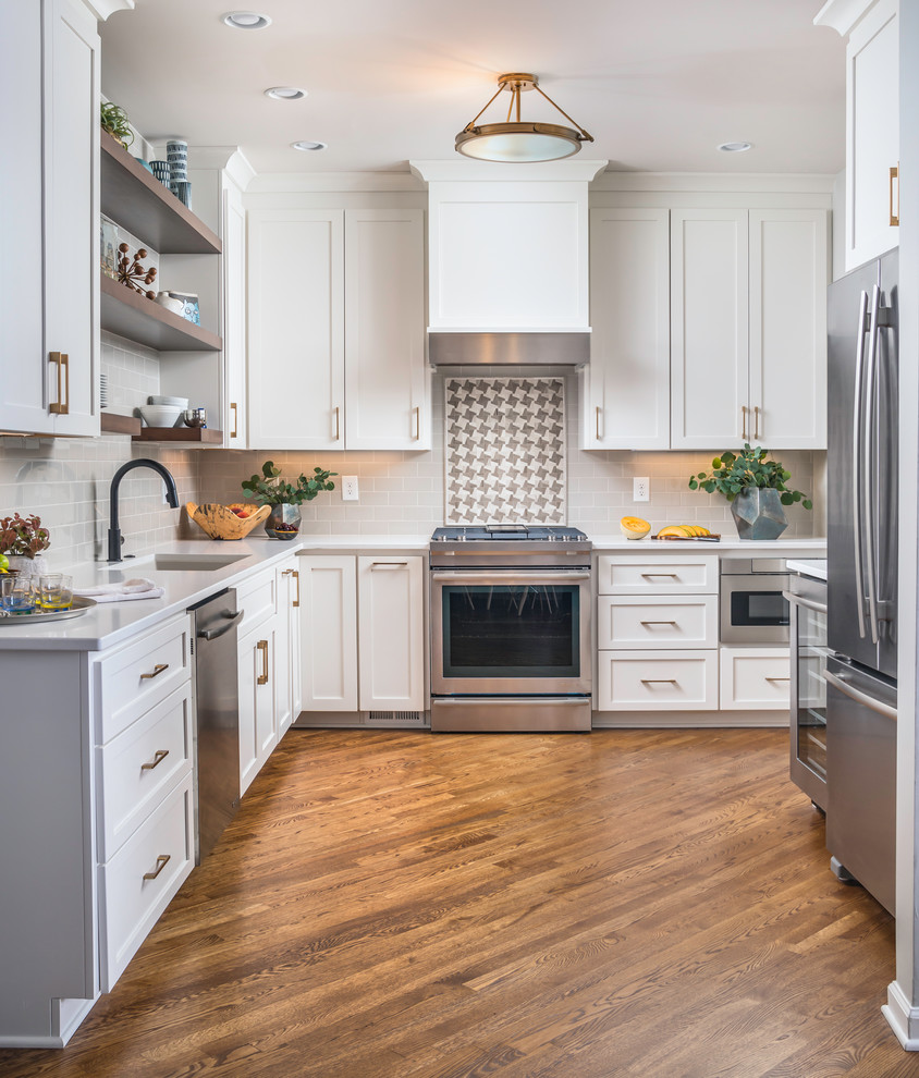 Design ideas for a classic l-shaped kitchen in Nashville with a submerged sink, shaker cabinets, white cabinets, grey splashback, metro tiled splashback, stainless steel appliances, dark hardwood flooring, no island, brown floors and white worktops.