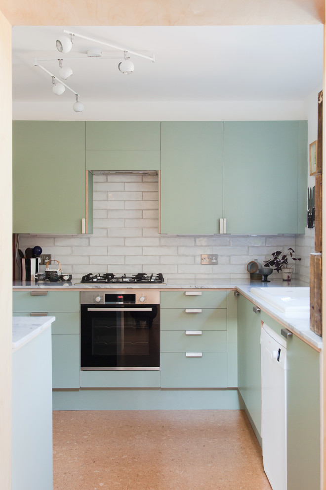 Foto på ett avskilt, litet funkis grå u-kök, med en dubbel diskho, släta luckor, gröna skåp, bänkskiva i kvartsit, grått stänkskydd, stänkskydd i keramik, vita vitvaror, korkgolv och brunt golv