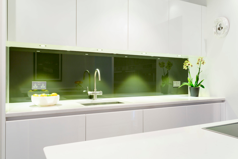 Diseño de cocina contemporánea con puertas de armario blancas, salpicadero gris, salpicadero de vidrio templado, electrodomésticos blancos y una isla