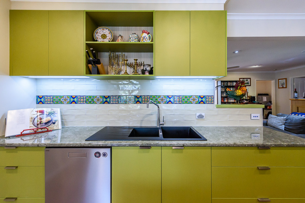 This is an example of a medium sized bohemian kitchen in Melbourne with a built-in sink, flat-panel cabinets, green cabinets, laminate countertops, multi-coloured splashback, ceramic splashback, ceramic flooring, an island and stainless steel appliances.