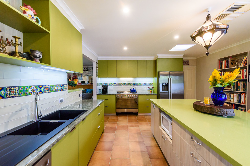 Medium sized eclectic kitchen in Melbourne with a built-in sink, flat-panel cabinets, green cabinets, laminate countertops, multi-coloured splashback, ceramic splashback, stainless steel appliances, ceramic flooring and an island.