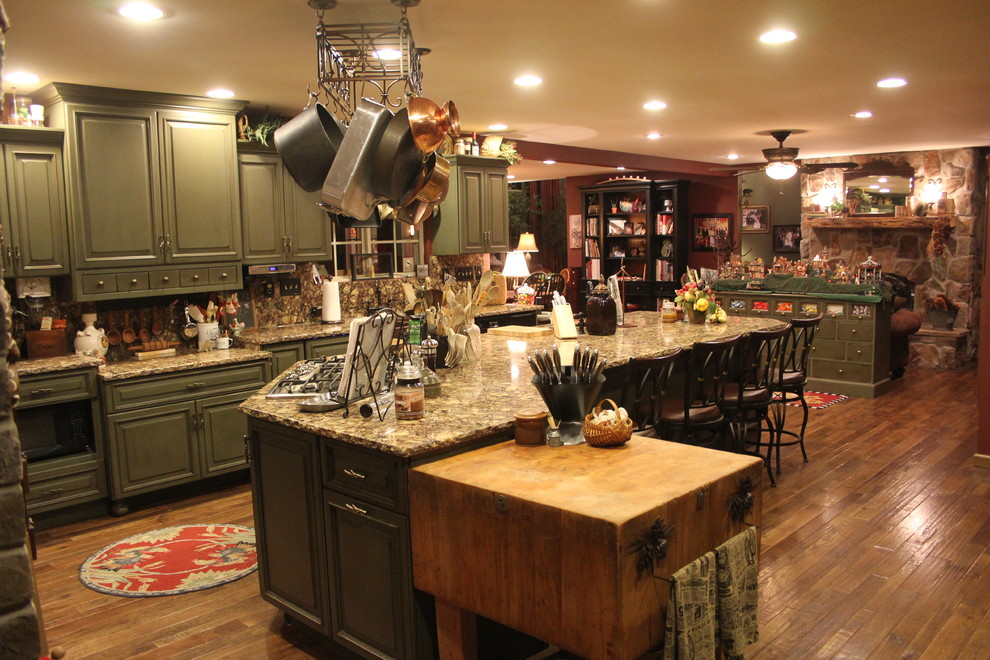 Foto på ett stort vintage kök, med luckor med upphöjd panel, gröna skåp, granitbänkskiva, brunt stänkskydd, rostfria vitvaror, mellanmörkt trägolv, en köksö och brunt golv