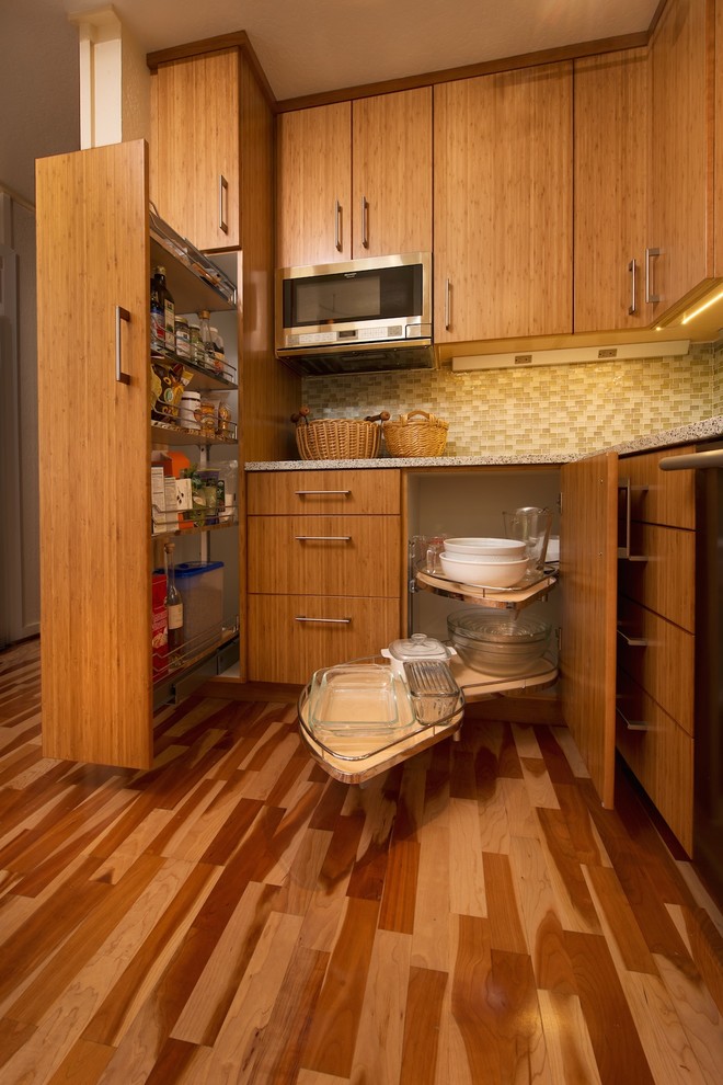Idéer för att renovera ett litet funkis kök, med en undermonterad diskho, släta luckor, skåp i mellenmörkt trä, bänkskiva i återvunnet glas, grönt stänkskydd, stänkskydd i glaskakel, rostfria vitvaror, mellanmörkt trägolv och en halv köksö