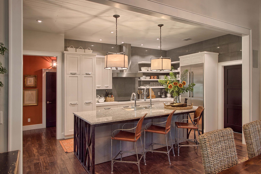 Large transitional l-shaped dark wood floor and brown floor open concept kitchen photo in Austin with shaker cabinets, gray backsplash, stainless steel appliances, an island, an undermount sink, gray cabinets, granite countertops and stone slab backsplash