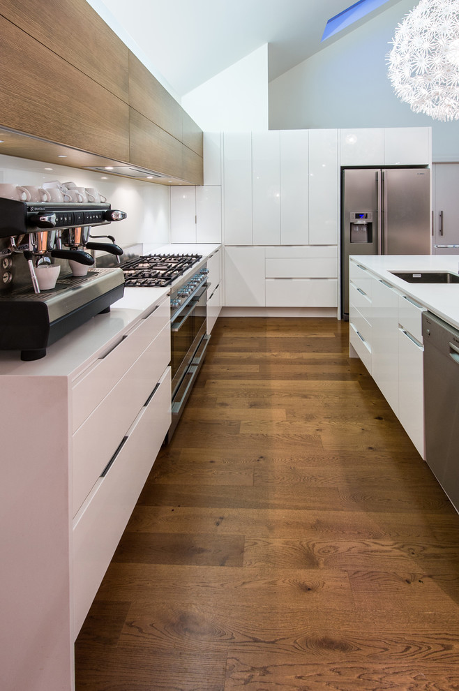 Trendy galley eat-in kitchen photo in Auckland with an undermount sink, flat-panel cabinets, quartz countertops, white backsplash, glass sheet backsplash and stainless steel appliances